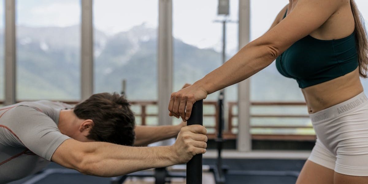A couple working out together at an indoor gym with mountain views.
