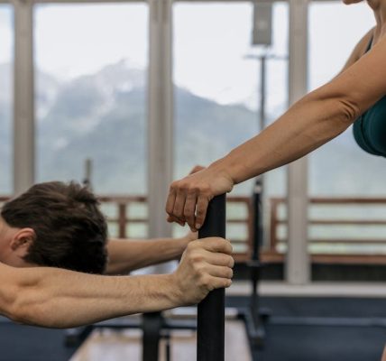 A couple working out together at an indoor gym with mountain views.