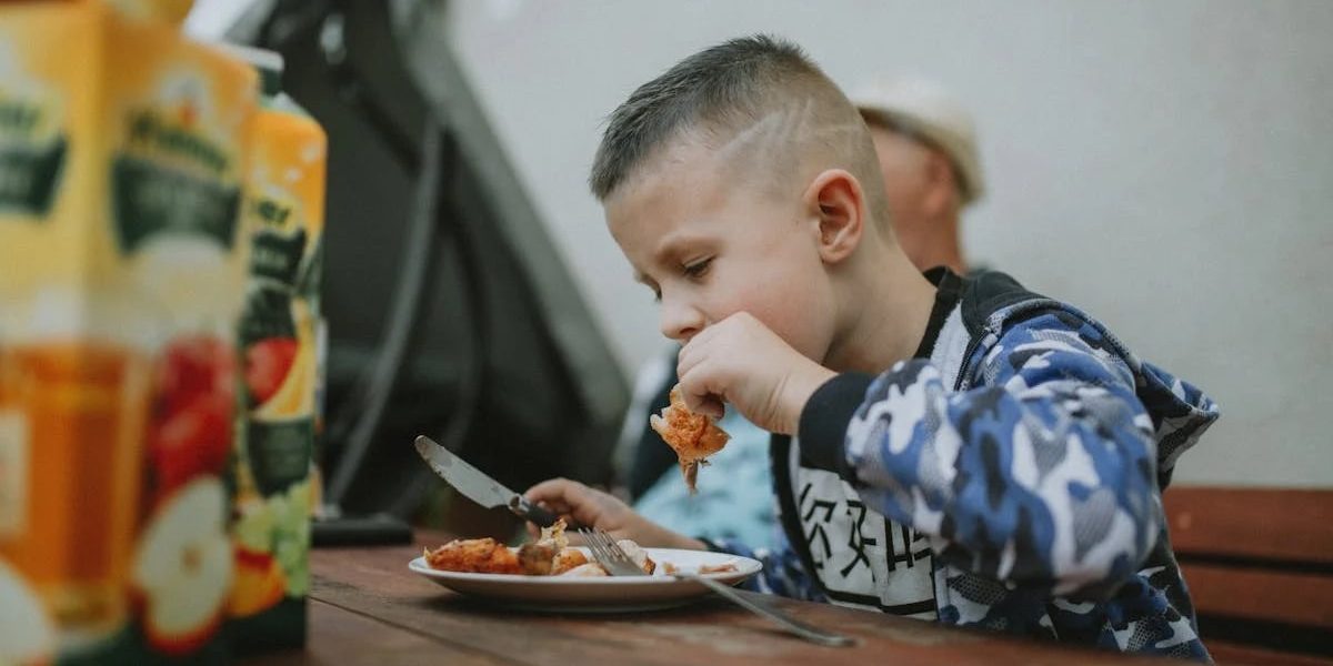 Young boy savoring a grilled chicken meal during an outdoor barbecue.