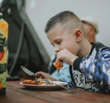 Young boy savoring a grilled chicken meal during an outdoor barbecue.